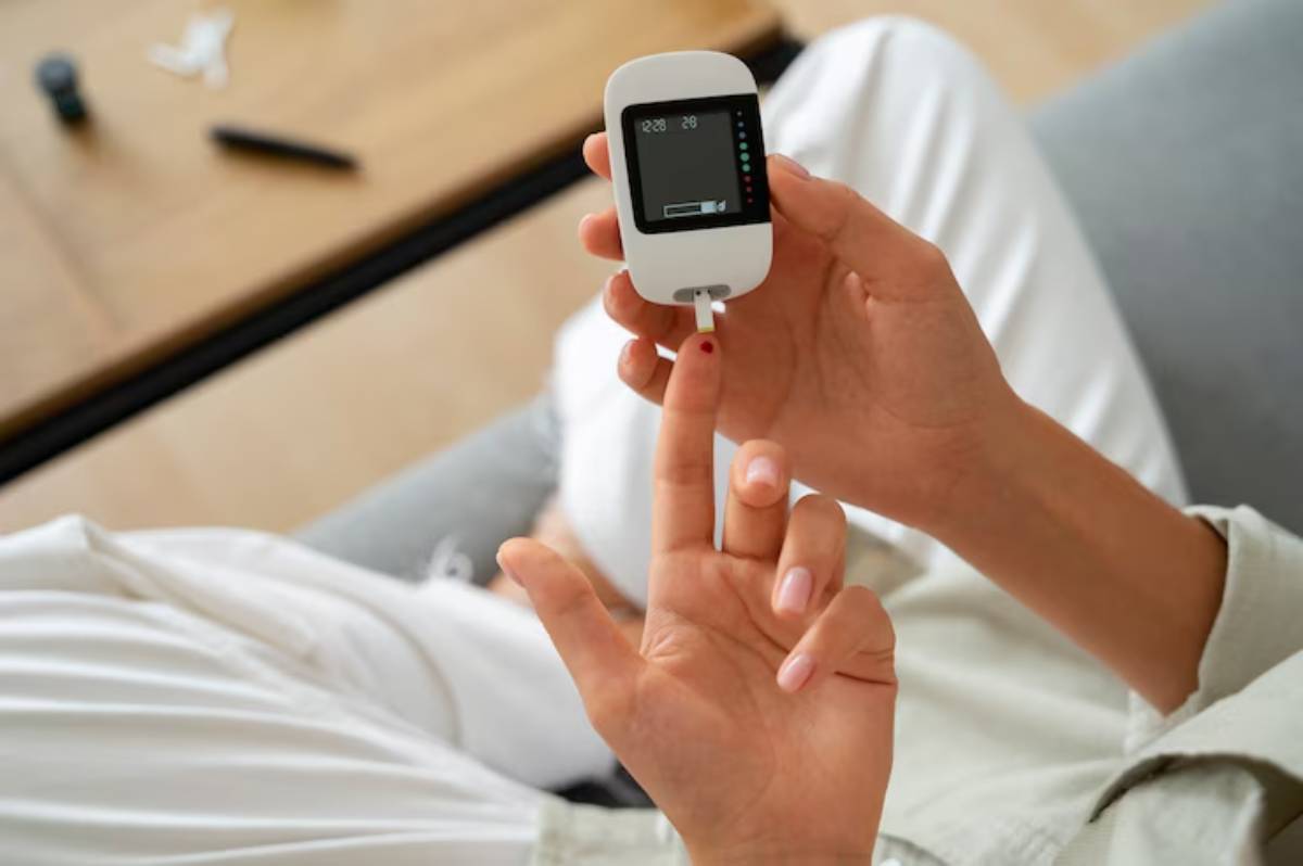 Close-up of a person using a glucose meter to check blood sugar levels, with a finger pricked and drops of blood visible.
