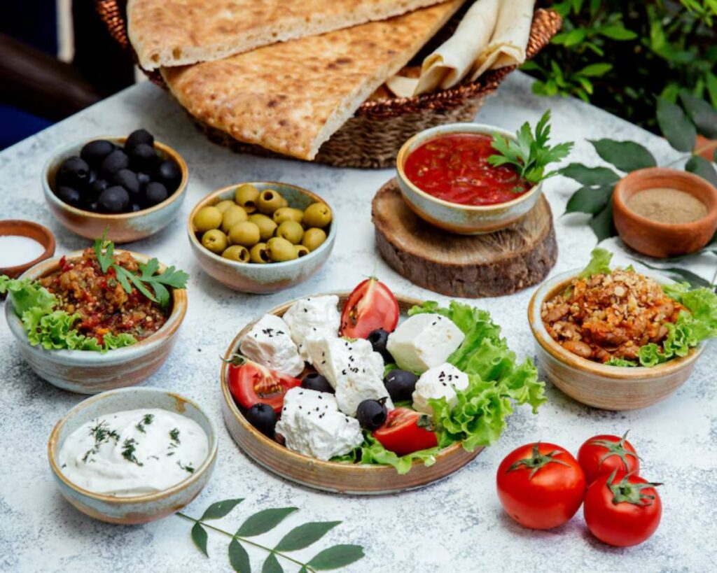 A vibrant spread of Mediterranean dishes including olives, feta, tomatoes, dips, and flatbread, garnished with fresh herbs.
